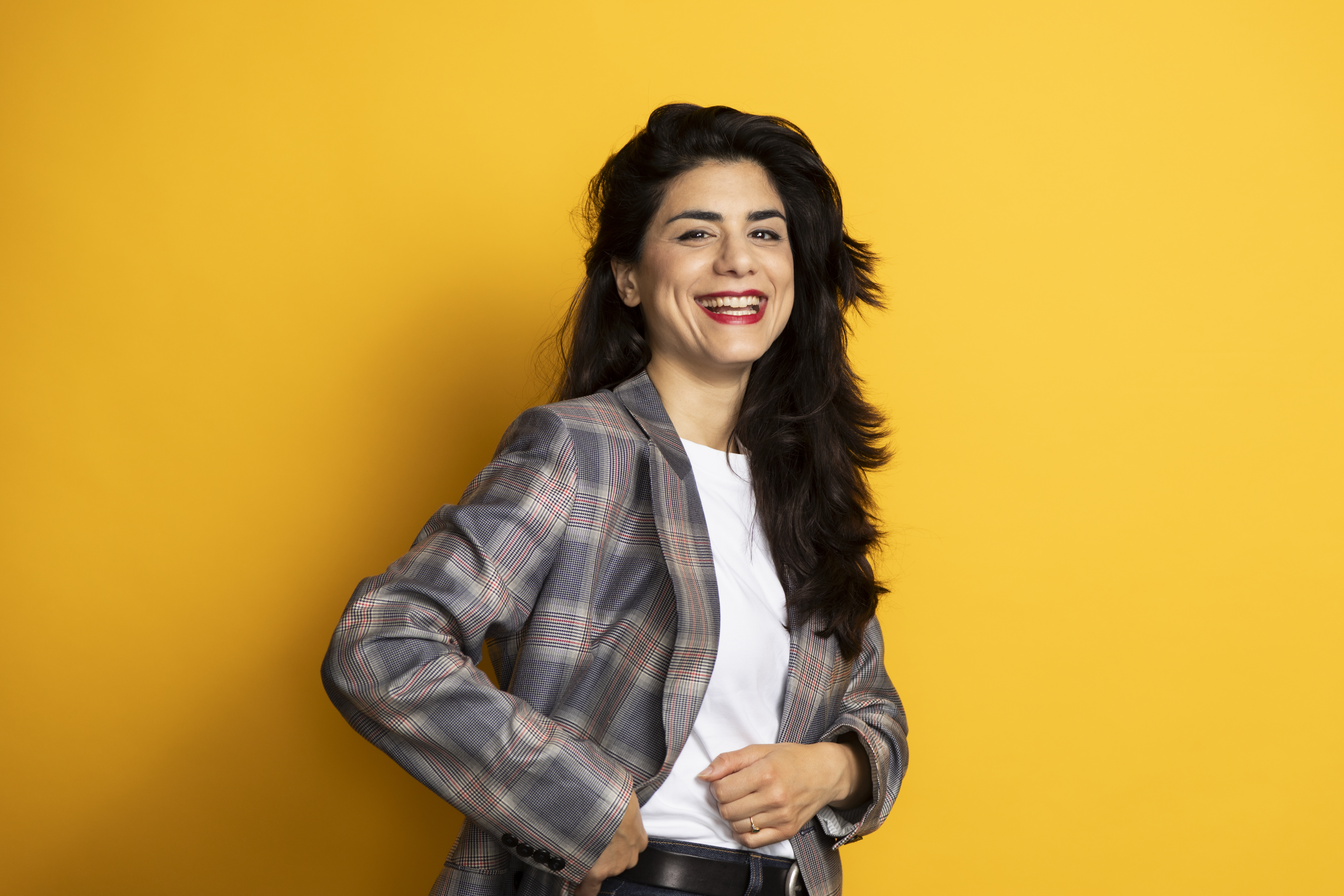 Een vrouw in een geblokt jasje tegen een witte achtergrond.