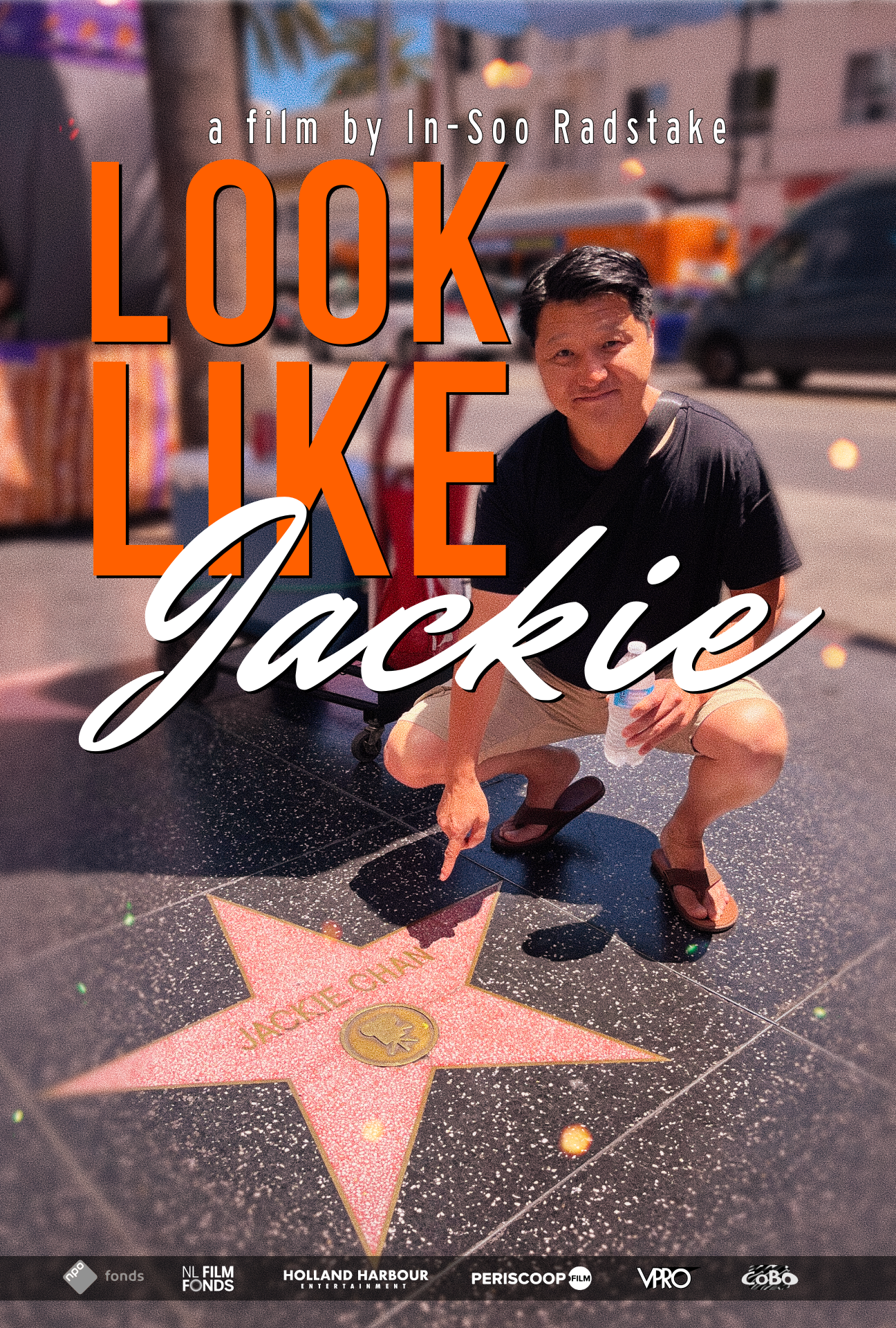 Een man zit gehurkt op straat en wijst naar een ster in de stoeptegel met de naam van Jackie Chan erin.