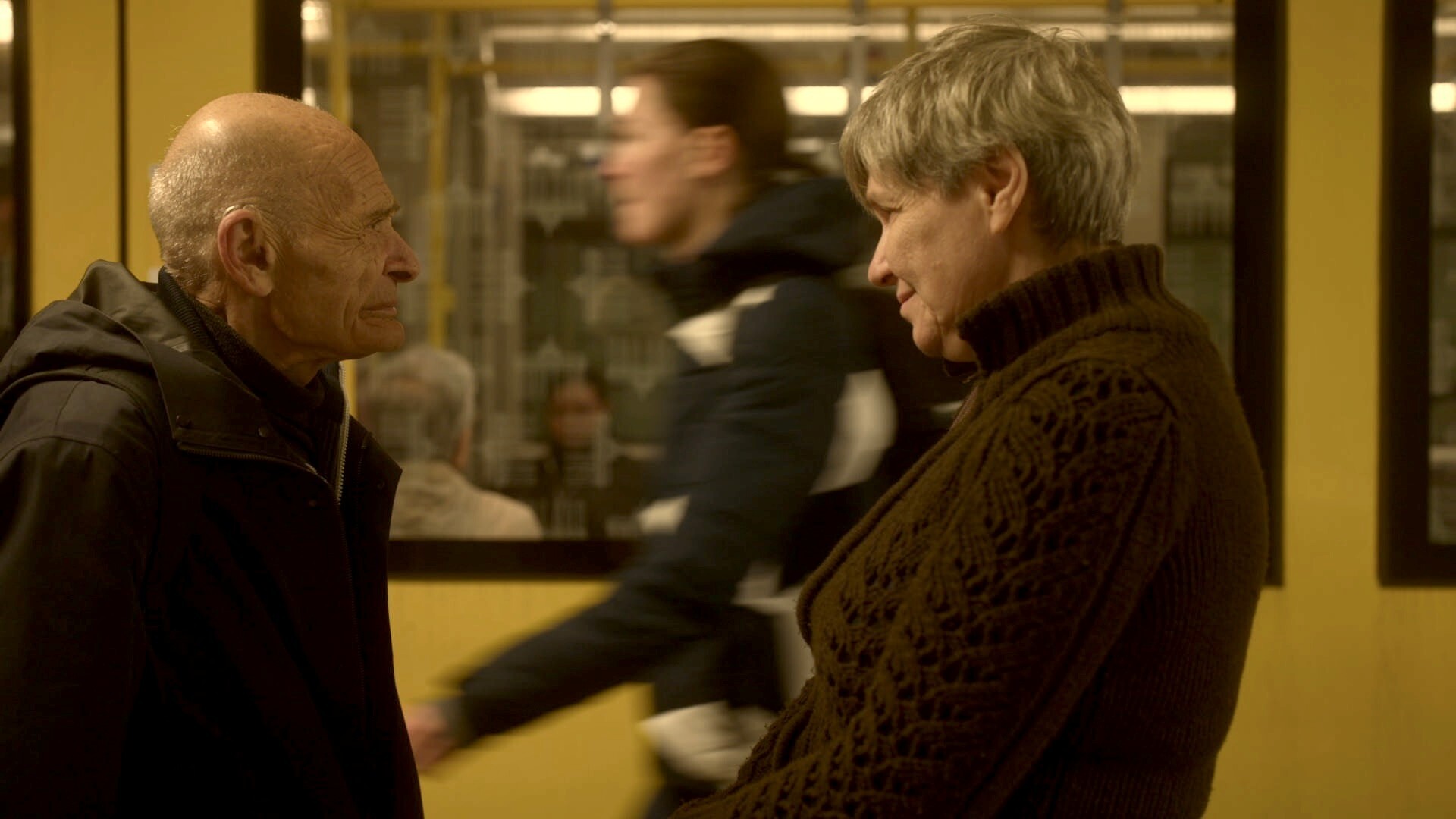 Een man en een vrouw kijken naar elkaar op een treinstation.