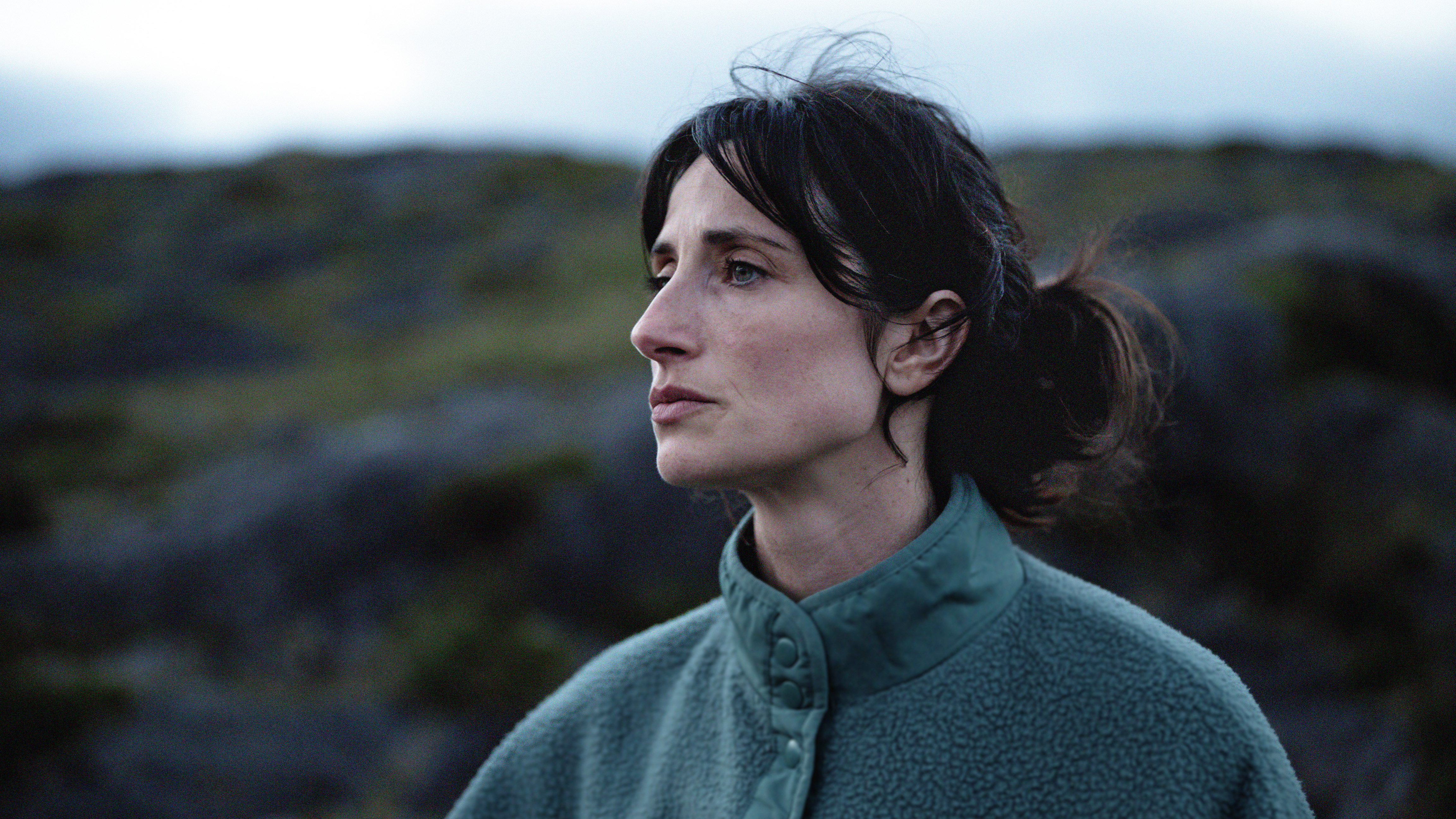 Een vrouw staat in de natuur en kijkt voor zich uit.