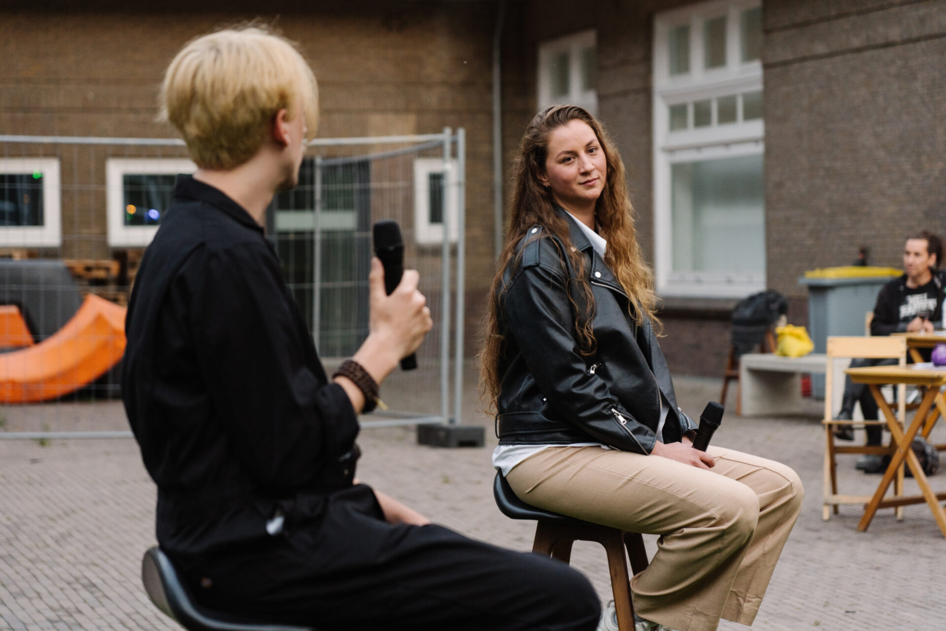 Twee personen op krukken met een microfoon in hun hand.