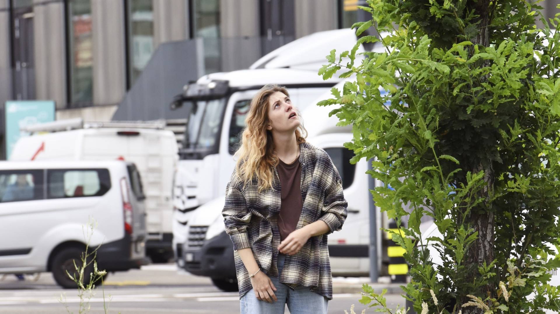 Een vrouw staat op straat en kijkt omhoog.